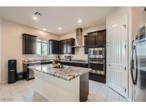 Modern kitchen featuring dark cabinetry, stainless steel appliances, and a center island with granite countertops at 92 Tesla Ridge Way, Las Vegas, NV 89183