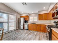 Bright kitchen featuring stainless steel appliances, wood cabinets, and sliding glass doors to the patio at 9292 Vervain Ct, Las Vegas, NV 89149