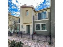 Two-story home featuring a quaint balcony, fenced patio, and modern architectural details and manicured landscaping at 2598 Mocha Pearl Ct, North Las Vegas, NV 89086