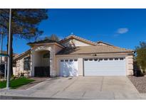 Single-story home with a beige exterior, desert landscaping, and a two-car garage under a clear blue sky at 297 Gingerbread St, Henderson, NV 89012