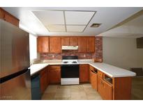Traditional kitchen featuring tile floors, wood cabinets, brick backsplash, and white countertops at 5612 W Lake Mead Blvd, Las Vegas, NV 89108