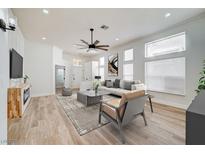 Bright and airy living room featuring a ceiling fan, neutral decor, and wood-look flooring at 7460 Desert Flame Ct, Las Vegas, NV 89149