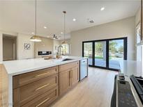 Modern kitchen features a center island with white countertops, wood cabinetry, and stainless steel appliances at 10412 Button Willow Dr, Las Vegas, NV 89134