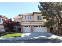 Two-story home with a three-car garage, desert landscaping, and a red tile roof at 10657 Blue Nile Ct, Las Vegas, NV 89144