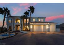 Elegant two-story home features a three-car garage, fountain, palm trees, and decorative stonework at dusk at 117 Milton Ct, Boulder City, NV 89005
