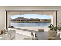 Bright living room with tiled floors, ceiling fans, and stunning lake view with access to the outside at 32 Grand Corniche Dr, Henderson, NV 89011