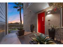 A modern home exterior featuring a vibrant red front door, stylish planters, and a view of a palm tree against a colorful sunset at 11441 Allerton Park Dr # 212, Las Vegas, NV 89135