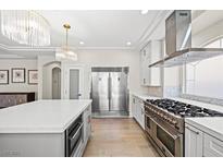 Modern kitchen features stainless steel appliances, white cabinets, an island, and wooden floor at 6335 Mount Eden Ave, Las Vegas, NV 89139