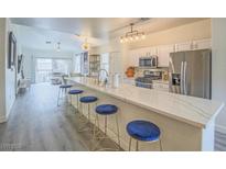 Bright open kitchen features a spacious island, modern appliances, and stylish blue seating at 817 Peachy Canyon Cir # 204, Las Vegas, NV 89144