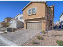 Two-story home featuring a brown stucco exterior, a two-car garage, and desert landscaping at 10279 Fragrant Apple Ct, Las Vegas, NV 89141