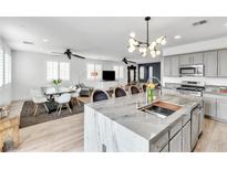 Bright open-concept living space featuring a modern kitchen with granite countertops and a dining area with sleek, white chairs at 10350 Mystic Pine Rd, Las Vegas, NV 89135
