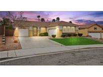 Charming single-story home with a well-manicured lawn, three-car garage, and decorative front door at twilight at 2295 Aria Dr, Henderson, NV 89052