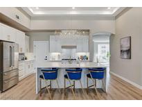 Modern kitchen features a large island with white marble countertops, stylish blue chairs, and stainless steel appliances at 2714 Langlade Ave, Henderson, NV 89052