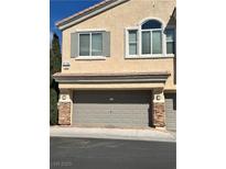 Beige two-story home featuring a two-car garage with stone accents and neutral trim at 8798 Tom Noon Ave # 103, Las Vegas, NV 89178