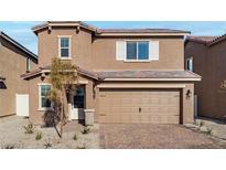 Charming two-story home with a tan exterior, desert landscaping, and a brick driveway at 1709 Desert Path Ave, North Las Vegas, NV 89032