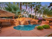 Backyard pool with rock waterfall feature, water slide, tropical landscaping, and outdoor seating at 1801 Glory Creek Dr, Las Vegas, NV 89128