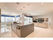 A stylish, open-concept kitchen featuring modern pendant lighting, a spacious island, and bright white flooring at 4087 Villa Rafael Dr, Las Vegas, NV 89141