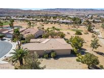 An elevated backyard view of this tan one-story home on a desert landscape, adjacent to a lush green golf course at 4963 Pensier St, Las Vegas, NV 89135