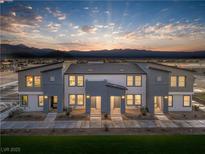 Modern townhomes with two-tone paint, neutral landscaping, and mountain views at dusk at 6165 Aster Garden St # 152, North Las Vegas, NV 89081