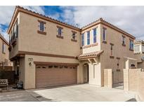 Two-story tan home with a two-car garage, tiled roof, and gated front porch at 682 Baffin Island Rd, Henderson, NV 89011