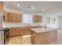 Charming kitchen features wood cabinets, granite countertops, stainless steel appliances, and a kitchen island at 7006 Feather Hill St, North Las Vegas, NV 89086
