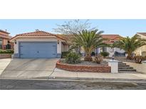 Charming single-story home featuring a terracotta tile roof, mature palm trees, and a blue garage door at 905 White Thunder St, Henderson, NV 89002