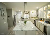 Bright kitchen with white cabinets, large island, stainless steel appliances and gray wood-look tile floors at 10323 Hardy Falls St, Las Vegas, NV 89141