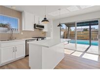 Bright kitchen featuring a central island, stainless steel appliances, and a sliding glass door leading to the pool at 2547 Wolverton Ave, Henderson, NV 89074