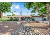 Charming single-story home with a rockscaped front yard, mature trees, and double red door at 3681 S Rosecrest Cir, Las Vegas, NV 89121