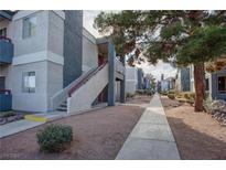 Apartment building featuring gray and white stucco exterior with landscaped walkway and second story entry at 8600 W Charleston Blvd # 1106, Las Vegas, NV 89117