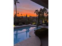Inviting pool area with sunset view, featuring lounge chairs and lush landscaping, perfect for relaxation and outdoor living at 181 Cliff Valley Dr, Las Vegas, NV 89148