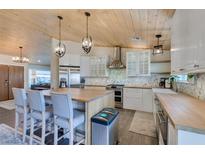 Bright kitchen boasts wood ceiling, island with seating, stainless steel appliances, and stylish countertops at 3083 Paintedhills Ave, Las Vegas, NV 89120