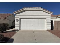 View of the garage of the home with a white garage door, brown rock landscaping, and a concrete driveway at 3761 Tohono Canyon St, Las Vegas, NV 89147