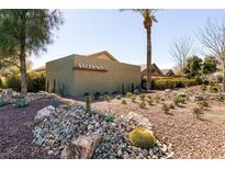 Community entrance view with professional desert landscaping, rock features, and mature trees at 4125 Gliding Gulls Ave, North Las Vegas, NV 89084