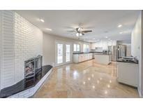 Bright living room features a brick fireplace, marble floors, ceiling fan, and access to a large kitchen with stainless steel appliances at 4170 Ridgecrest Dr, Las Vegas, NV 89121