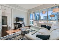 Modern living room featuring a white sectional sofa and stunning city views through large windows at 4525 Dean Martin Dr # 2001, Las Vegas, NV 89103
