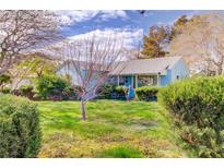 Charming single-story blue home featuring mature landscaping and a well-maintained front yard at 648 Utah St, Boulder City, NV 89005