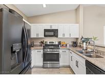 Well-lit kitchen features stainless steel appliances, modern white cabinets, and stone countertops at 6539 Ozzie Harriet Ave # 101, Las Vegas, NV 89122