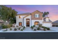 Charming two-story home with stone accents, lush landscaping, and a welcoming entrance at dusk at 2694 Caumsett Ct, Las Vegas, NV 89117