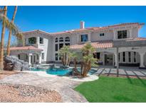 Luxury backyard pool with rock features, tropical landscaping, and covered patio area at 3465 Pama Ln, Las Vegas, NV 89120