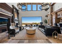 An expansive living room features high ceilings, elegant chandeliers, a large screen tv, and a sweeping outdoor view at 64 Promontory Ridge Dr, Las Vegas, NV 89135