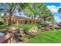 Stunning backyard view with lush landscaping, water feature and mature trees providing ample shade at 7803 Canoe Ln, Las Vegas, NV 89145