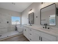 This bathroom features double sinks, two mirrors, a tub, and a glass shower at 793 Vortex Ave, Henderson, NV 89002