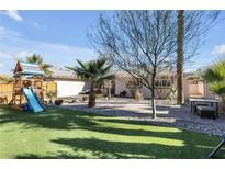 This backyard features a lush lawn, desert landscaping, a custom patio, and a charming playset at , Las Vegas, NV 89121