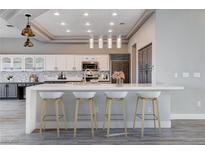 Modern kitchen boasts white cabinets, quartz countertops, mosaic backsplash, and stainless steel appliances at 3012 Anna Bay Dr, Las Vegas, NV 89134