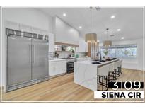 Bright kitchen boasts stainless appliances, waterfall island with seating, and stylish pendant lighting at 3109 Siena Cir, Las Vegas, NV 89128