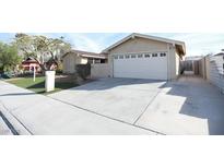 Tan single-story home featuring a two-car garage and a well-maintained lawn with mature landscaping at 3905 E Cherokee Ave, Las Vegas, NV 89121