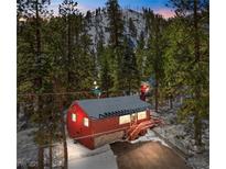 Charming red cabin nestled in the woods with snow-covered roof and welcoming entrance at 4165 Mont Blanc Way, Mount Charleston, NV 89124