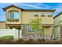 Charming two-story home featuring tan stucco, decorative stonework, and a well-manicured front yard at 6110 Scarlet Leaf St, Las Vegas, NV 89148