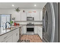 Modern kitchen featuring stainless steel appliances and granite countertops, wooden floors and white cabinetry at 7456 Cooks Meadow St, North Las Vegas, NV 89084